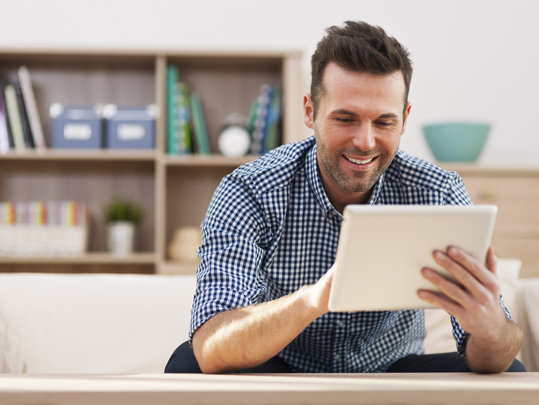 Smiling handsome man using digital tablet at home